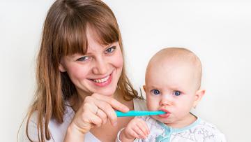 Baby brushing teeth with mom